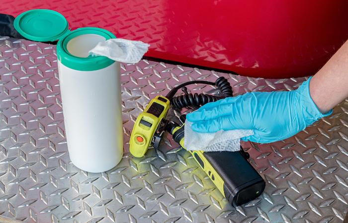 woman sanitizes walkie talkie