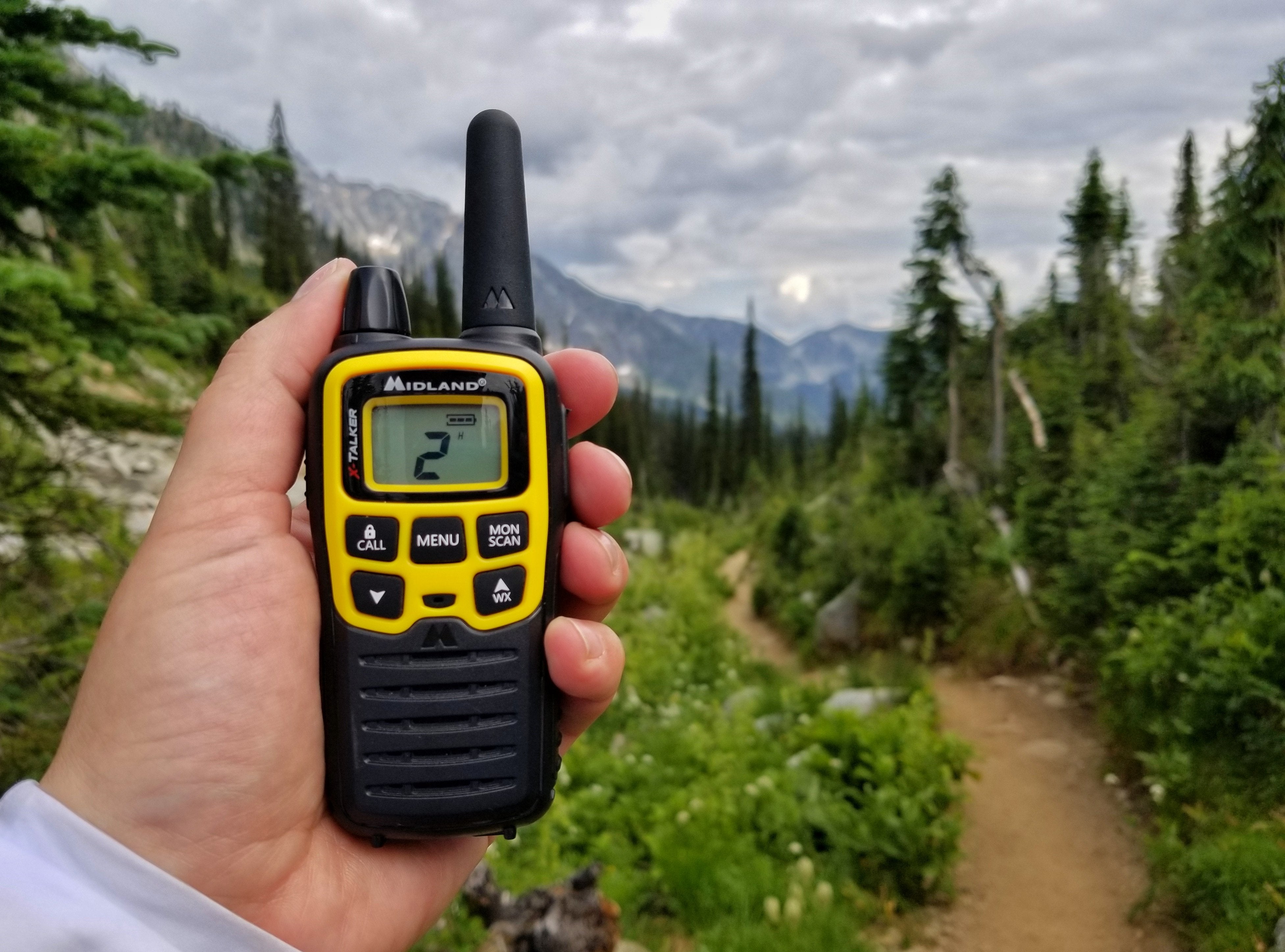 yellow walkie talkie in hand with forest in background