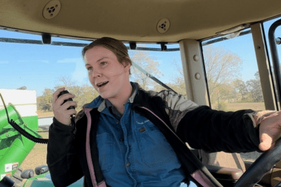 female farmer uses Midland GMRS two-way radio mic in tractor cab