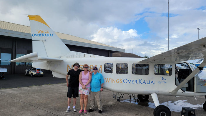 woman stands by small plane with family