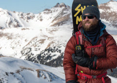 Person in winter clothing with a backpack against a snowy mountain background