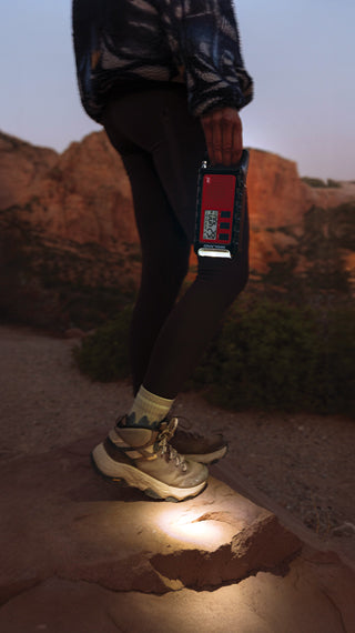 Person standing on a rock with a weather radio in desert mountains 